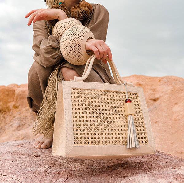 Bolsa Teresa na cor off white na mão da modelo em um cenário como o deserto.